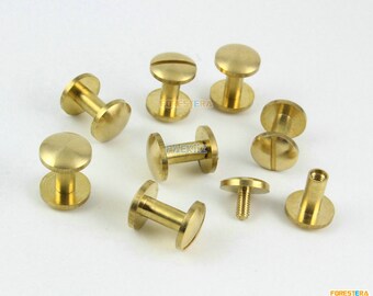 May include: A collection of ten brass screw-on studs, some with a slotted head and some with a round head. The studs are arranged on a white surface.