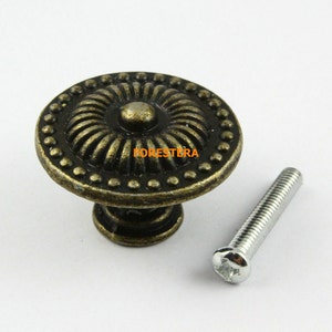 May include: Antique bronze cabinet knob with a decorative floral design and a matching screw.