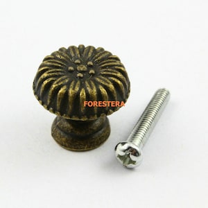 Pode incluir: Botão de armário de latão antigo com um design floral decorativo e um parafuso correspondente.