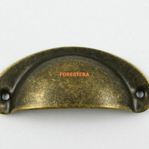 Op de afbeelding: Een vintage-stijl, antiek messing komvormige kastgreep met een verweerde afwerking. De greep heeft twee gaten voor montage en een licht afgeronde rand.