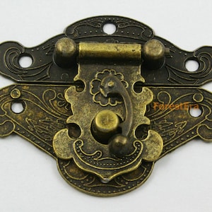 May include: Antique brass latch with ornate floral design. The latch has a decorative handle and two small knobs.