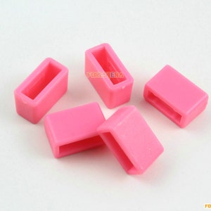 May include: Five pink plastic slider buckles. The buckles are rectangular with a small opening in the center.