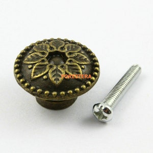 May include: A bronze-colored cabinet knob with a floral design and a beaded edge. The knob comes with a silver screw.