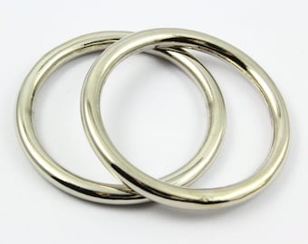 May include: Two silver-colored metal rings, slightly overlapping, against a white background. The rings are circular with a smooth, reflective surface. The image is well-lit, highlighting the metallic sheen of the rings.