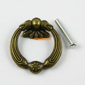 May include: Antique bronze ring pull cabinet door handle with a decorative floral design and a matching screw.