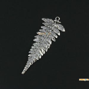 Op de afbeelding: Een zilveren varen hanger met een lus om aan een ketting of armband te bevestigen. De hanger is gedetailleerd met een getextureerd oppervlak en een realistisch varen ontwerp.