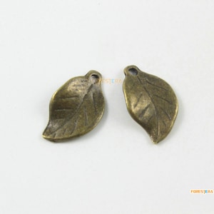 May include: Two antique gold leaf charms with a detailed leaf design. The charms have a hole at the top for attaching to jewelry or other crafts.