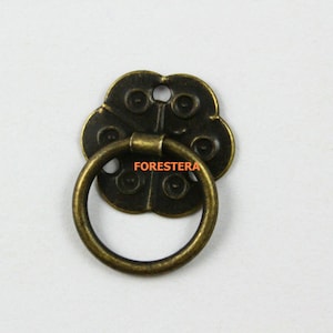 May include: Antique bronze cabinet pull with a decorative flower-shaped backplate and a ring handle.
