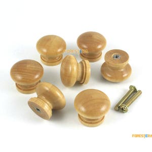 Può includere: Sette pomelli in legno in diverse tonalità di marrone chiaro. I pomelli sono rotondi con un bordo rialzato e una superficie liscia. Sono perfetti per aggiungere un tocco rustico ai mobili.