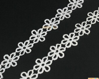 May include: White lace trim with a delicate floral pattern. The trim features small, evenly spaced flowers with a scalloped edge.