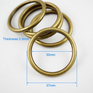 以下が含まれることがあります： 金色の金属製のリングが4つあり、それぞれ直径8.9cmです。リングは互いに積み重ねられています。リングの厚さは8.9cmです。