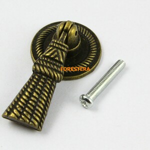 May include: A gold-toned cabinet knob with a rope-like design and a matching screw. The knob has a round base and a tall, tapered handle.