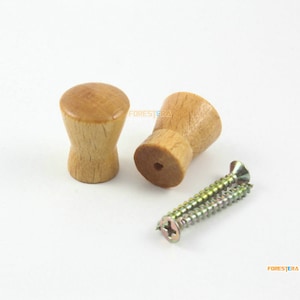 May include: Two wooden knobs with a natural finish and two screws. The knobs are round with a slightly tapered shape. The screws are silver.