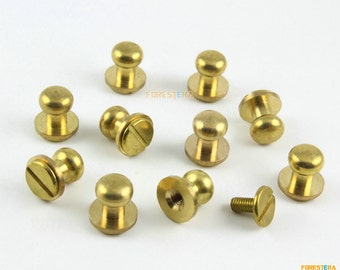 Könnte beinhalten: Nahaufnahme von zehn Messingknöpfen mit einer einzelnen Schraube. Die Knöpfe sind rund mit einer erhabenen Mitte und einer flachen Basis. Die Schraube ist ebenfalls aus Messing und hat einen Schlitz.