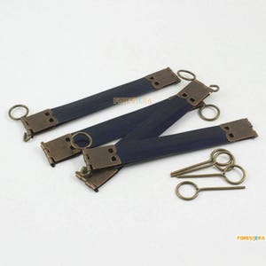 Könnte beinhalten: Vier antike Messingverschlüsse mit blauen Stoffbändern und zwei Messing-Schlüsseln. Die Verschlüsse haben ein dekoratives Design und sind perfekt, um jedem Projekt einen Vintage-Touch zu verleihen.