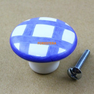 May include: White ceramic cabinet knob with a blue and white checkered pattern. The knob has a round top and a screw-on base. A silver screw is included.