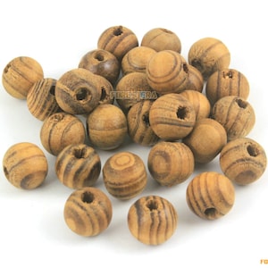 Puede incluir: Un montón de 20 cuentas de madera natural con rayas marrones y tostadas. Las cuentas tienen un agujero en el centro para enhebrar.