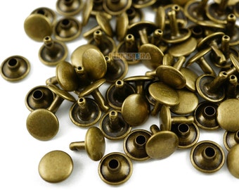 May include: A pile of antique brass-colored metal rivets. The rivets have a round head and a post with a hole in the center. The rivets are used for attaching leather, fabric, or other materials.
