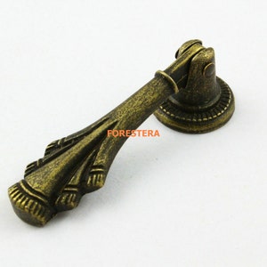 May include: Antique brass cabinet pull with a decorative floral design and a round base.