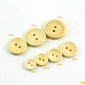 May include: Assortment of 10 wooden buttons in various sizes, ranging from 1.15 inches to 2.5 inches in diameter. The buttons are a light beige color and have a stitched edge.