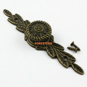 May include: Antique brass cabinet hardware with a decorative floral design and a round knob. The hardware comes with two screws.