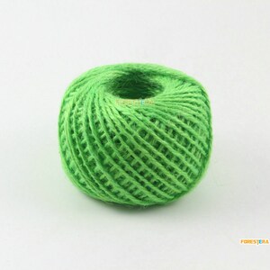 Puede incluir: Una bola de cuerda verde brillante hecha de fibras naturales de yute. La cuerda está bien enrollada y lista para proyectos de artesanía.