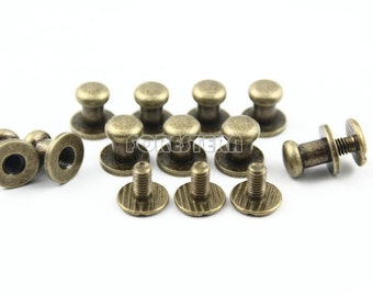 May include: A set of 12 antique gold-toned metal push buttons. The buttons have a round head and a threaded shank. Some buttons are shown with a matching screw.
