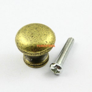 Pode incluir: Uma maçaneta de metal dourado com topo redondo e um parafuso para instalação.