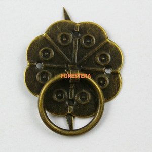 May include: Antique brass drawer pull with a decorative flower-shaped design and a ring handle. The pull has a distressed finish and a rustic look.