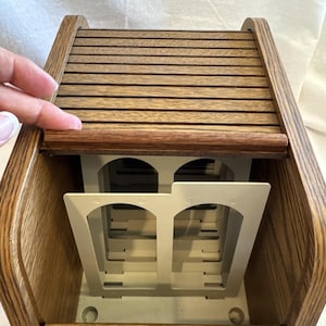 Op de afbeelding: Een houten opbergdoos met een rolluikdeksel dat openschuift om een reeks interne verdelers van gebroken wit plastic te onthullen. De doos heeft een afwerking met een medium bruine houtnerf.