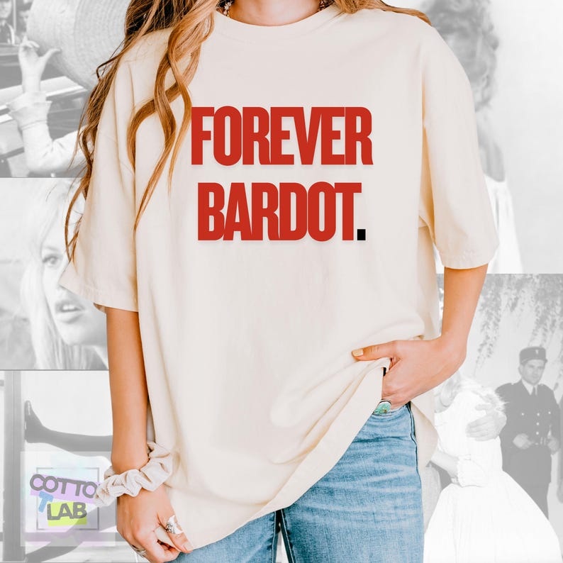 May include: Cream-colored t-shirt with the text "FOREVER BARDOT" in bold red letters. The shirt is a relaxed fit and is paired with blue jeans. The overall aesthetic is casual and vintage-inspired.