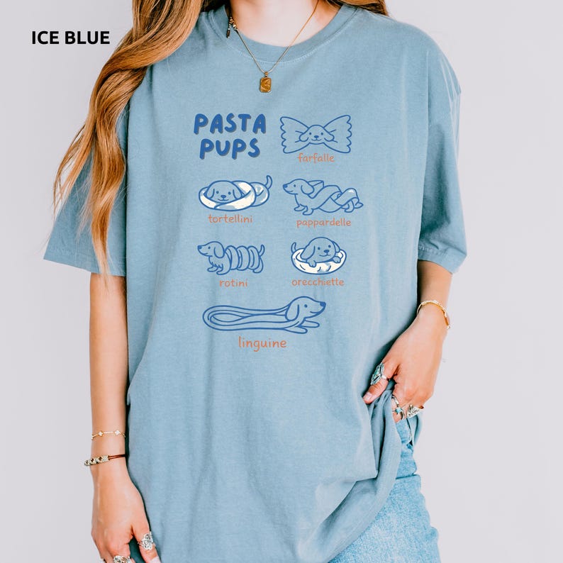 May include: Ice blue t-shirt with the text "PASTA PUPS" and illustrations of pasta shapes with dog faces. The shirt features drawings of farfalle, tortellini, pappardelle, rotini, orecchiette, and linguine.