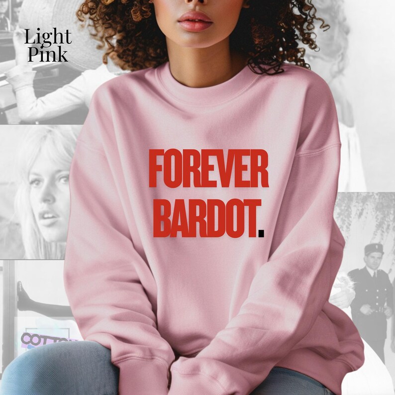 May include: Light pink sweatshirt with the text "FOREVER BARDOT" in red. The sweatshirt is a crew neck style. The words are in a bold, sans-serif font. The sweatshirt is a solid color.