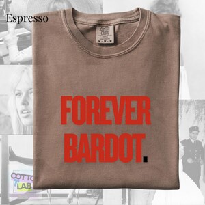 May include: Espresso-colored Comfort Colors t-shirt with the text "FOREVER BARDOT" in red block letters. The shirt has a crew neck and a tag at the neckline. The background features a collage of black and white images.