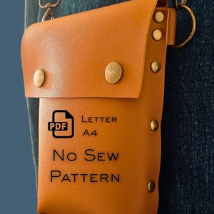 May include: A tan leather pouch with a flap closure, secured by brass-colored rivets and snap closures. The pouch has a shoulder strap and a PDF pattern label that reads "LETTER A4 No Sew PATTERN".