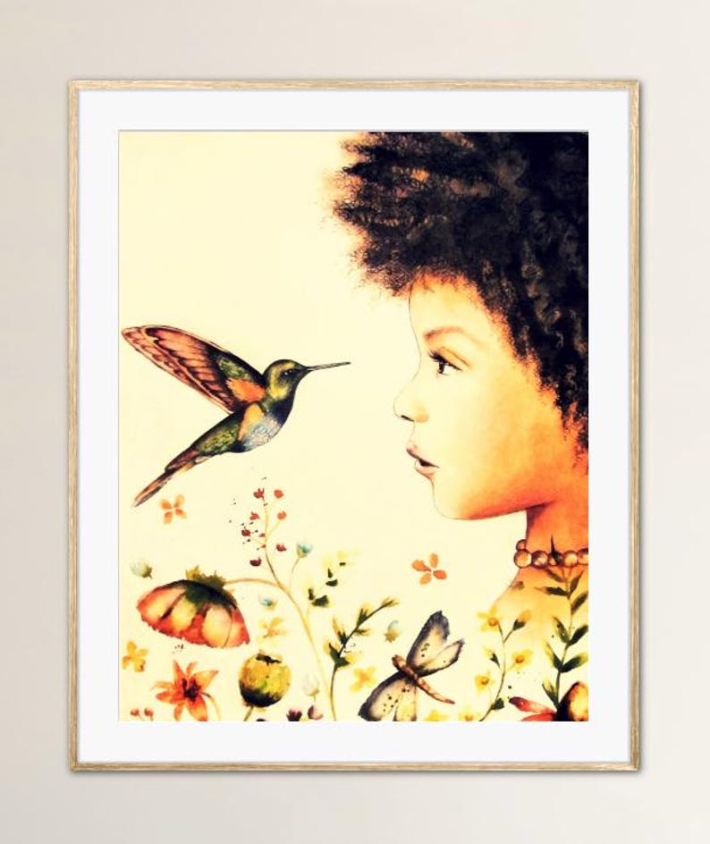 May include: A framed watercolour print depicting a young person observing a hummingbird in flight. The artwork features a vibrant hummingbird with colourful wings, set against a backdrop of flowers and a soft, yellow background. The print is in a wooden frame.