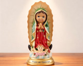 May include: A religious figurine of the Virgin of Guadalupe, featuring a red and green robe with gold accents. The statue has a halo and a cherub at the base. The base is gold and has the text "Virgen de Guadalupe".