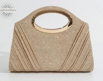 May include: A gold clutch bag with a glittery finish and a gold handle. The handbag has a rectangular shape with vertical pleats on the front. The handle is a gold oval shape.