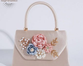 Bolso satinado con flores decorativas y asa superior