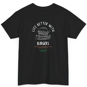 以下が含まれることがあります： 白いハンバーガーのグラフィックと「LIFE BETTER WITH BURGERS」の文字が入った黒いTシャツ。その下には「EVERY BITE IS A MASTERPIECE OF FLAVOR TEXTURE AND PURE JOY」と書かれています。