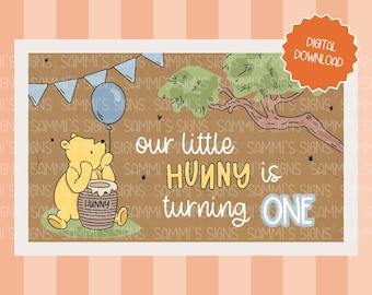 May include: A digital download featuring Winnie the Pooh. The illustration shows Pooh Bear with a honey pot, a blue balloon, and the text "our little Hunny is turning ONE." The design includes a tree and a banner.