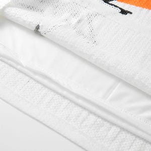 May include: Close-up of a white sequined fabric with an orange and black design. The fabric is layered over a white lining. The sequins create a textured surface, reflecting light.
