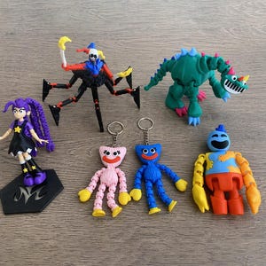 Puede incluir: Una colección de figuras articuladas de colores, que incluyen un bufón, un dinosaurio, una muñeca y varios personajes de llaveros. Las figuras son de plástico y presentan colores brillantes como el rosa, el azul, el verde y el amarillo.