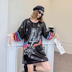 May include: Black sequined dress with a lightning bolt and star design. The sleeves have colorful stripes at the cuffs. The model is wearing a black beret and sunglasses. The text on the magazine reads "COOL & CHIC".