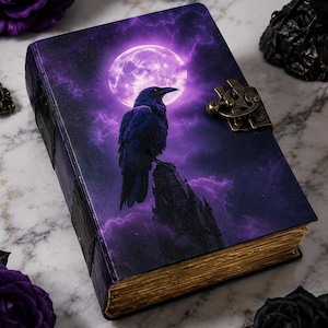 May include: A rectangular journal with a purple cover featuring a black raven perched on a spire under a full moon. The book has a metallic latch closure on the side and gold-toned page edges, presenting a detailed graphic illustration on the front.