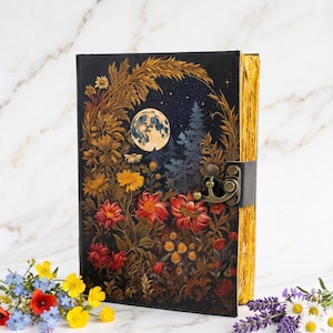May include: A black rectangular journal featuring a full-color illustration of a night scene with a full moon, pine trees, and vibrant red, orange, and yellow flowers. The book has a metallic bronze-colored latch and gold-toned page edges.
