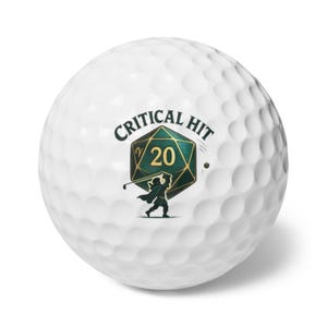 May include: White golf ball with a dimpled surface. The ball features a graphic of a green and gold die with the text "CRITICAL HIT" and a golfer swinging a club. A fun gift for golfers and D&D fans.