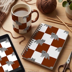 May include: A coffee mug, spiral notebook, and tablet, all featuring a brown and white checkered pattern with gray raccoon illustrations. A ball of brown yarn, knitting needles, and scissors are also present. The text "MRSHaggard" is visible.