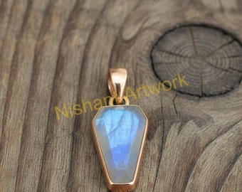 Op de afbeelding: Een roségouden hanger met een rechthoekige, facetgeslepen, blauwe edelsteen. De hanger heeft een eenvoudige beugel voor een ketting. De achtergrond is een houten oppervlak. De tekst "Nishan Artwork" is zichtbaar.