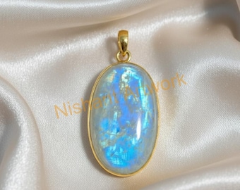 May include: Oval-shaped pendant with a gold-colored frame and bail. The pendant features a large, iridescent, blue and white stone. The background is a cream-colored, satin-like fabric. The pendant is a piece of jewelry.